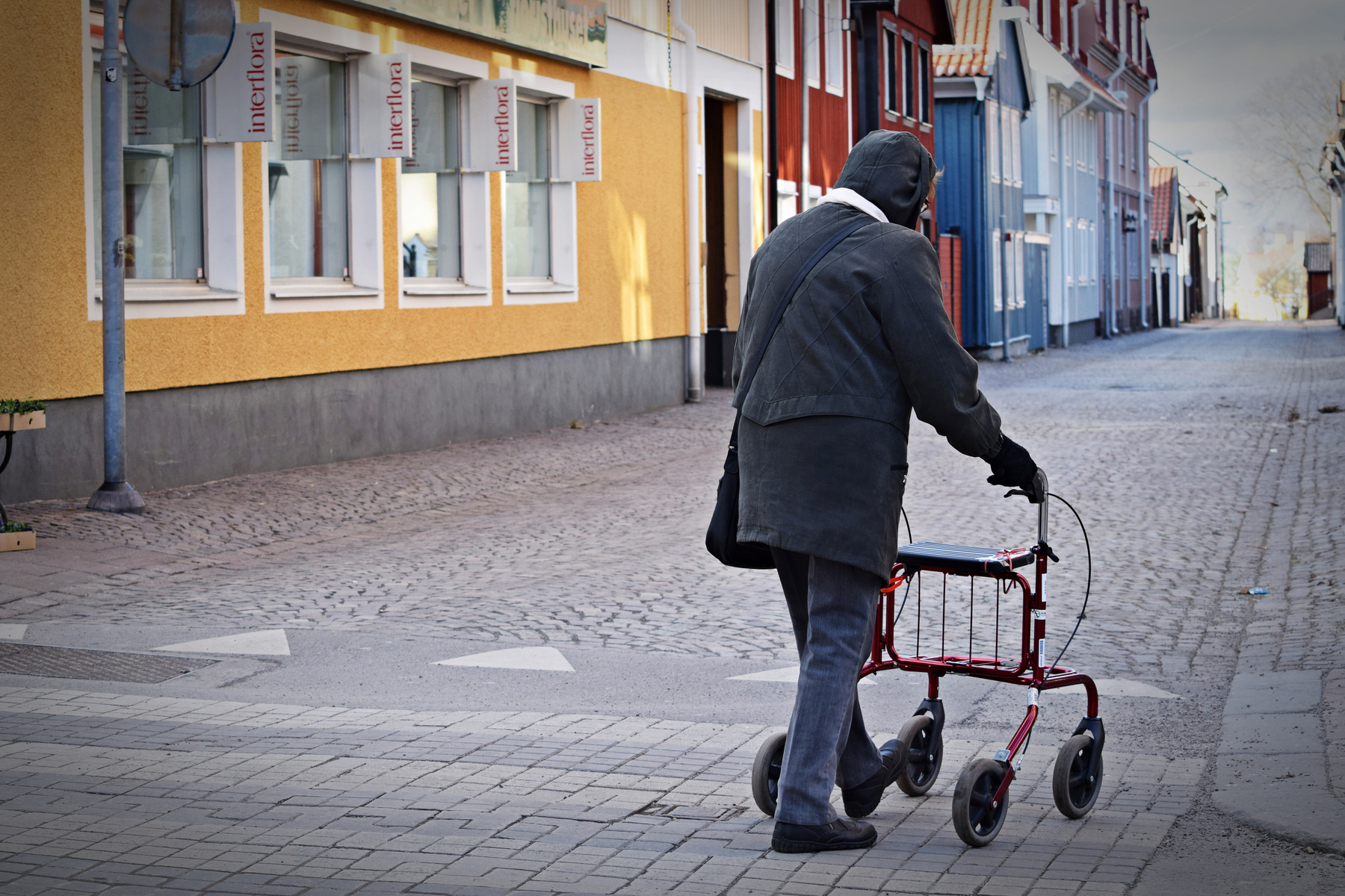 Ensam pensionär går på en gata i en småstad