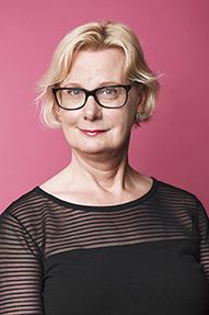 Porträttbild Anna-Carin Bylund. Anna-Carin har kort blont hår, svarta glasögon och en svart tröja.