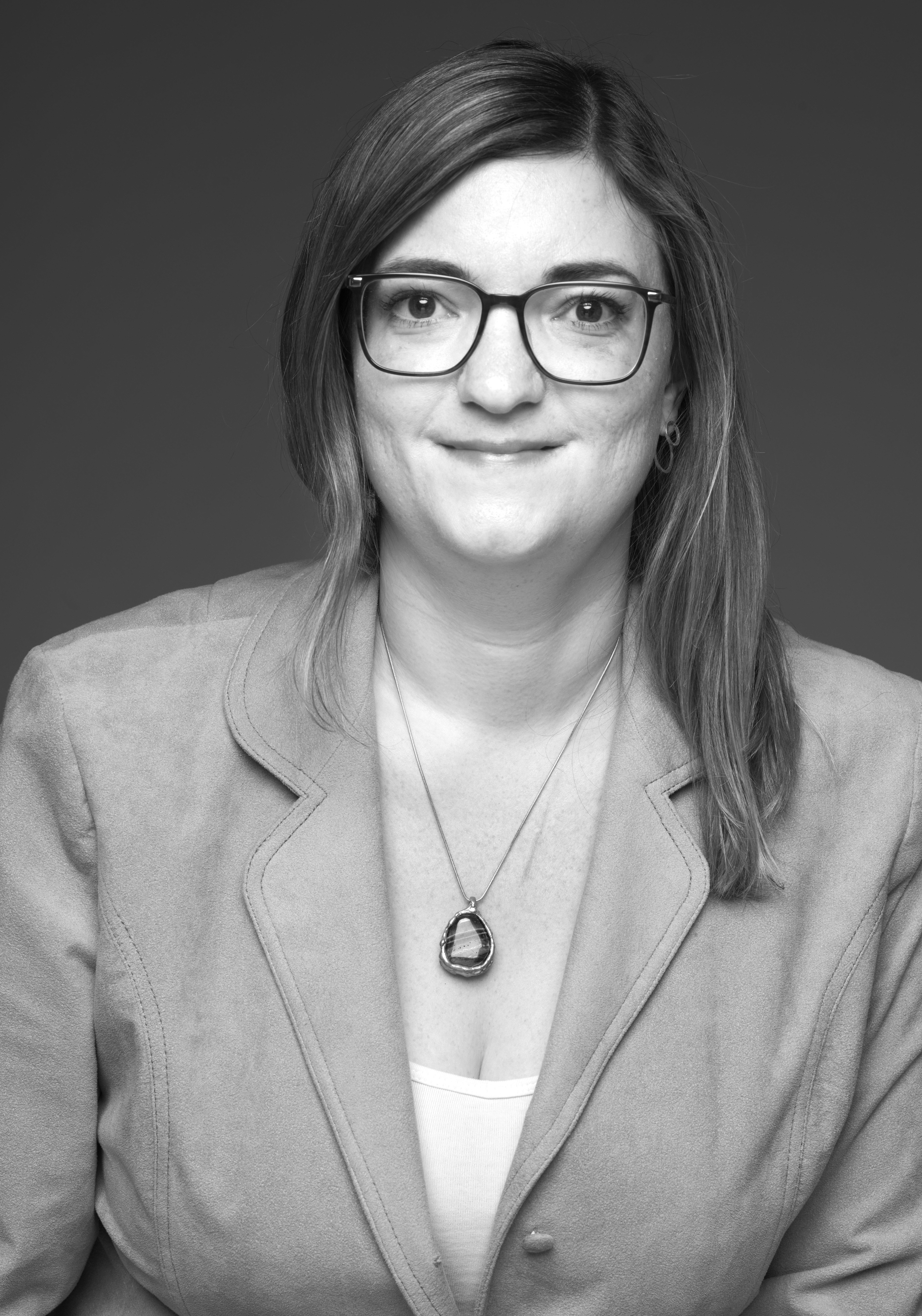 Svartvitt porträtt av Charlotte Ovesson. Hon har långt hår och glasögon, hon tittar lugnt in i kameran.