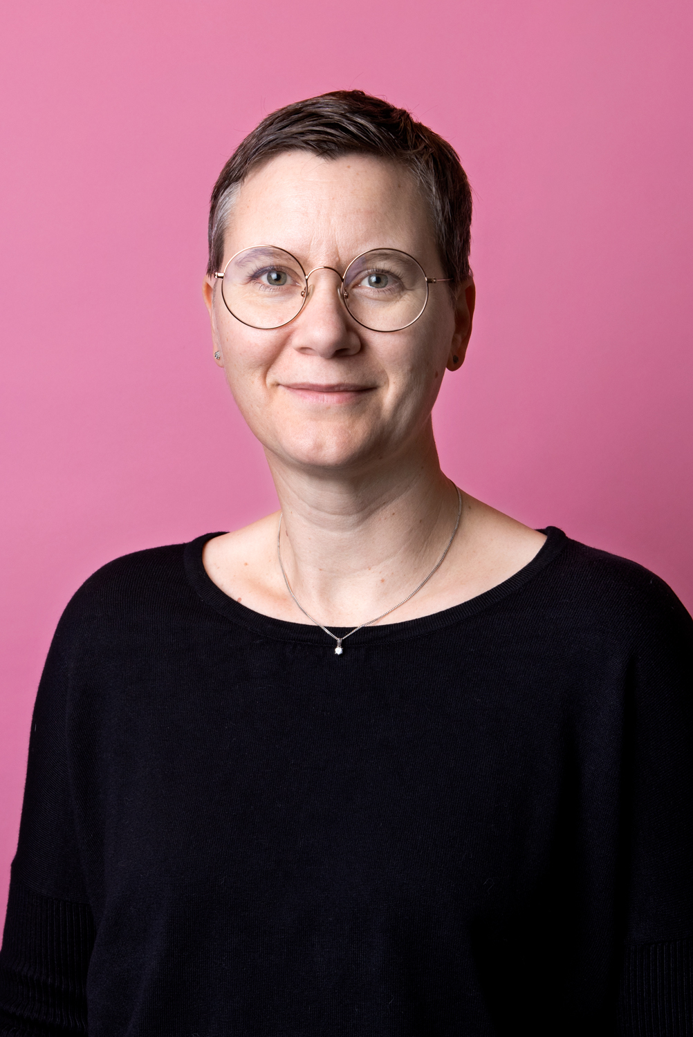 Porträttbild Annika Stigmark. Annika har kortklippt hår och runda glasögon.