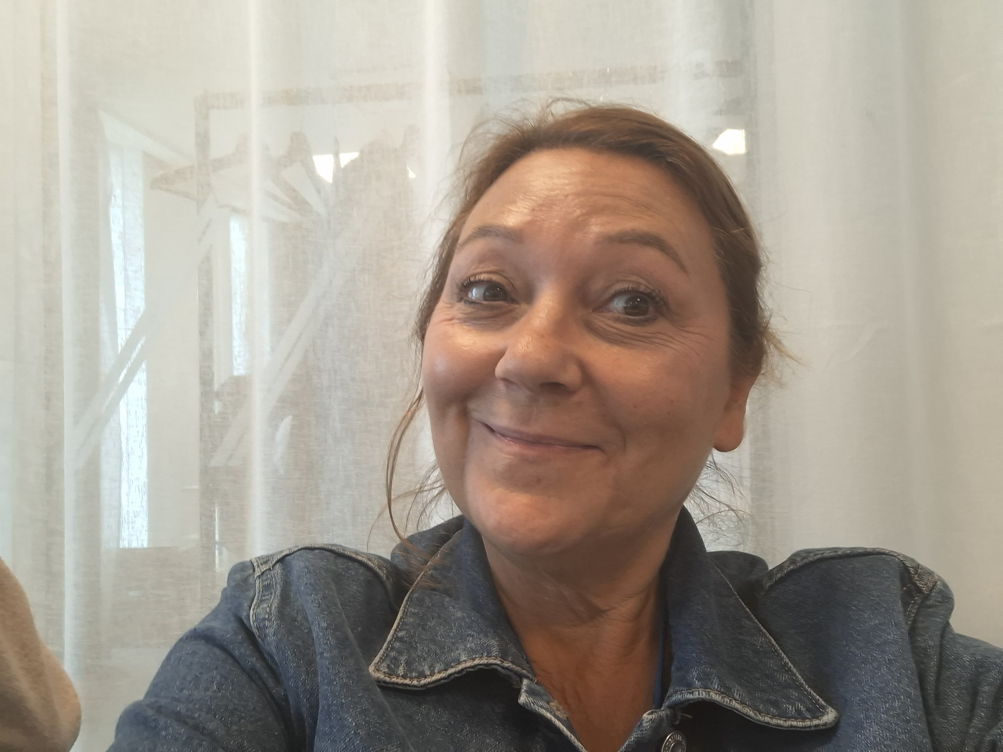 Jeanette tar en selfie, hon har en jeansskjorta på sig och ser glad ut.