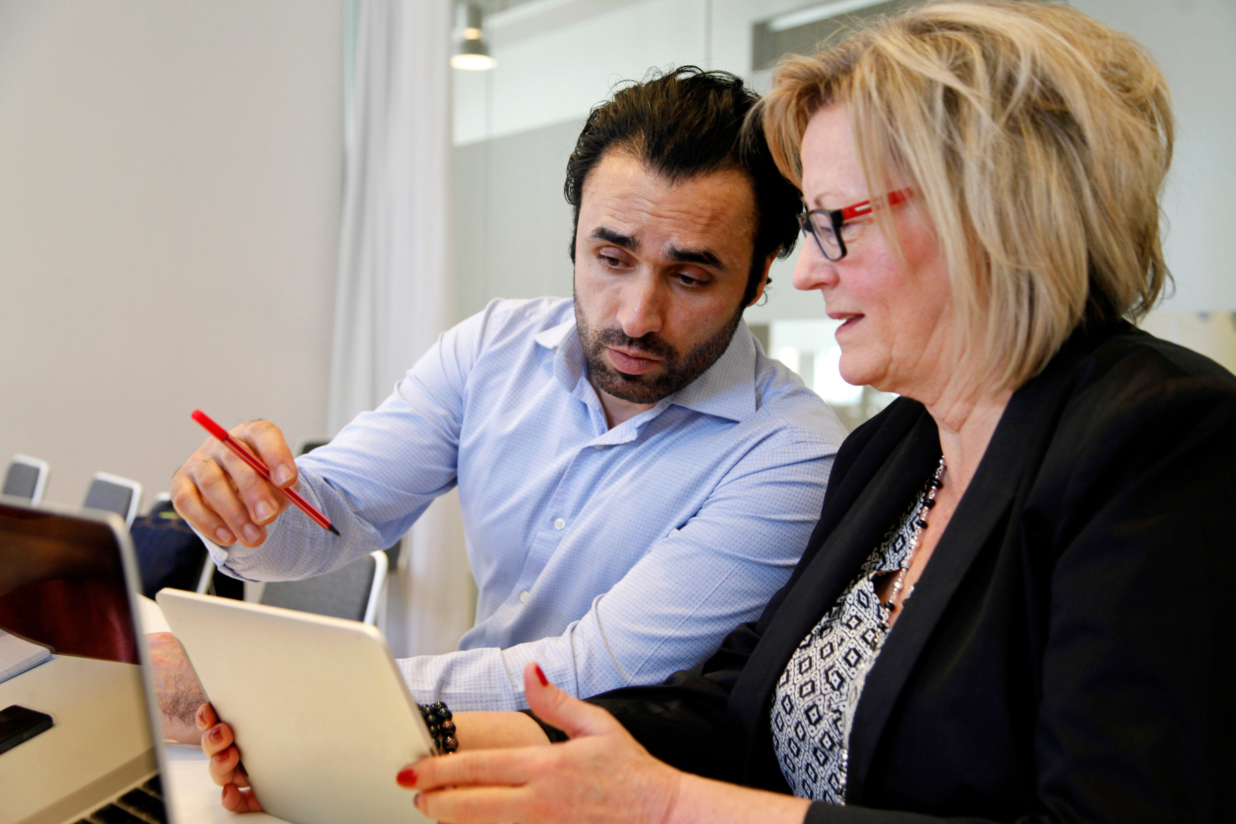 Två handläggare tittar på en skärm och diskuterar något.