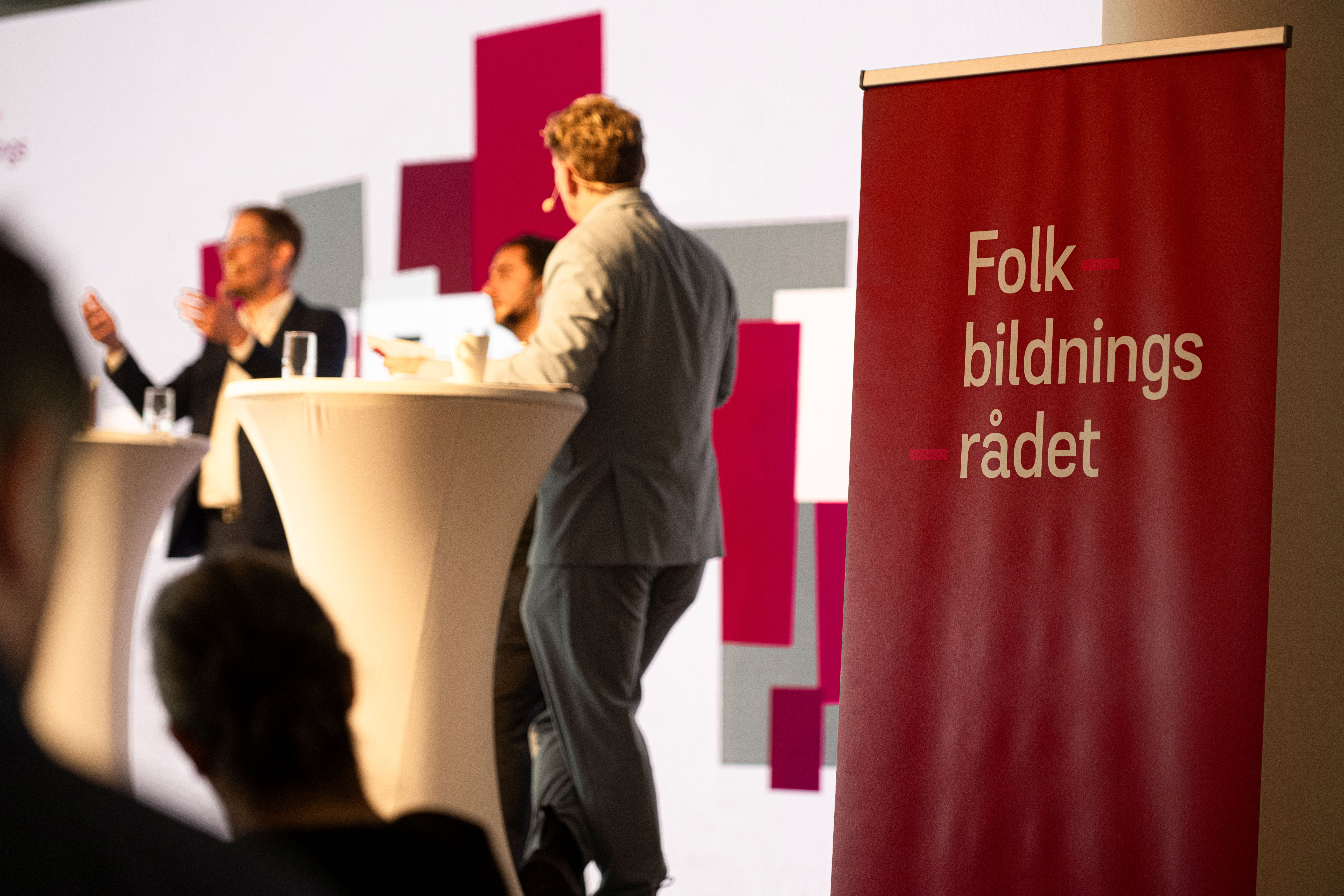 En panel diskuterar på konferens. I förgrunden syns en roll up med Folkbildningsrådets logotyp.
