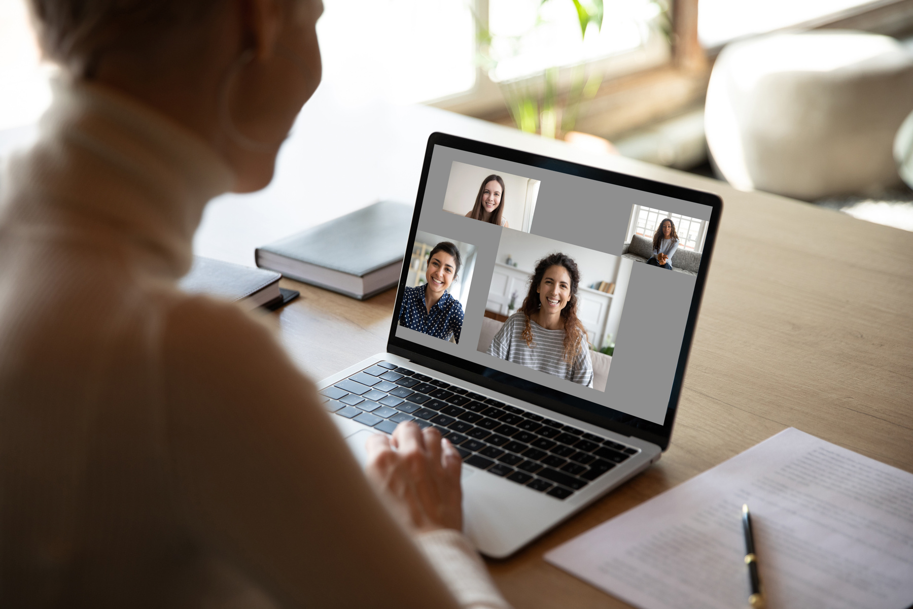Siluett av person framför laptop där ett videosamtal pågår. 