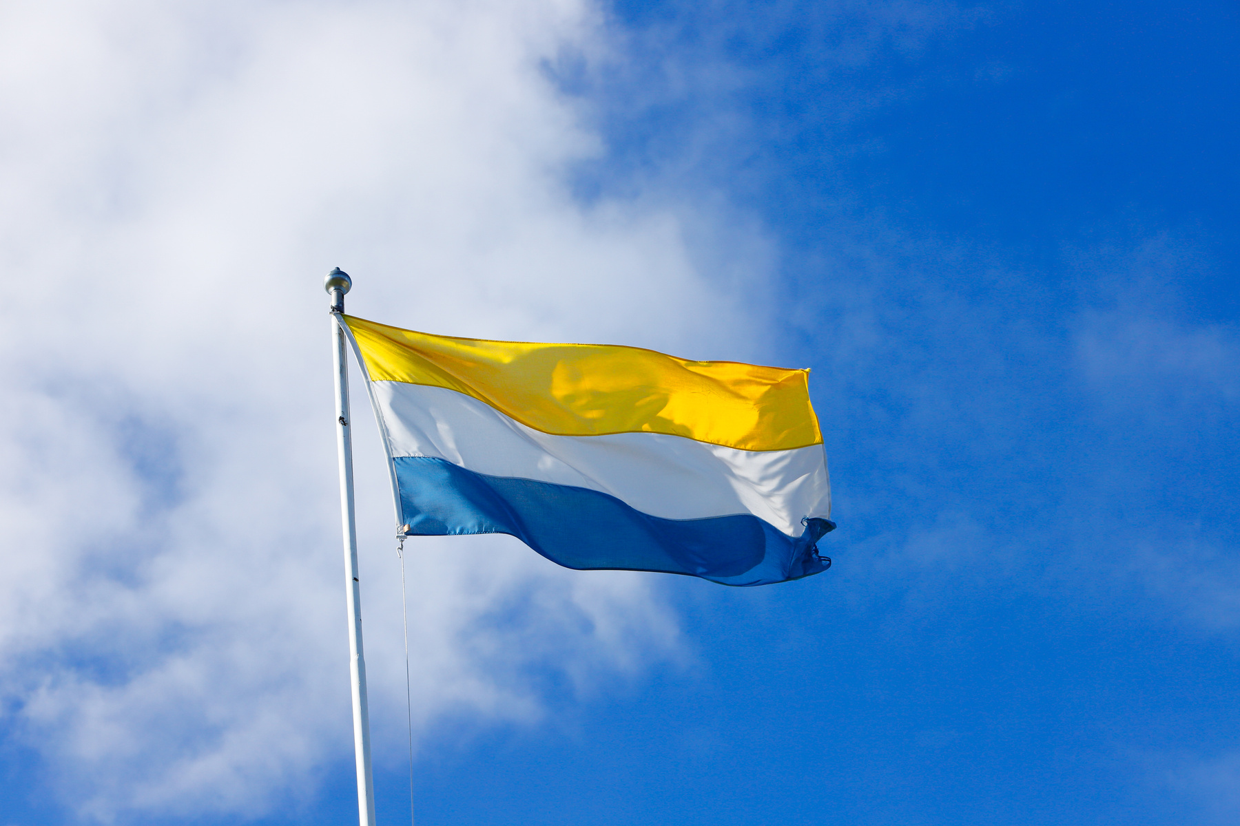 Tornedalens flagga vajar mot en blå himmel.