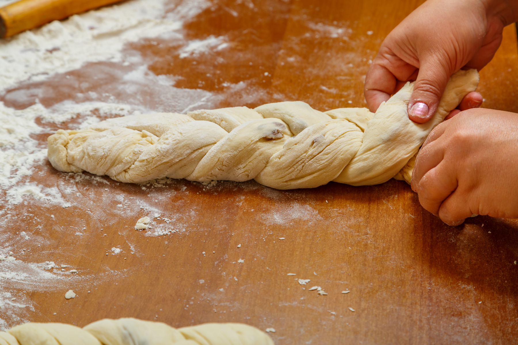 Ett par händer flätar det traditionella judiska brödet challa.