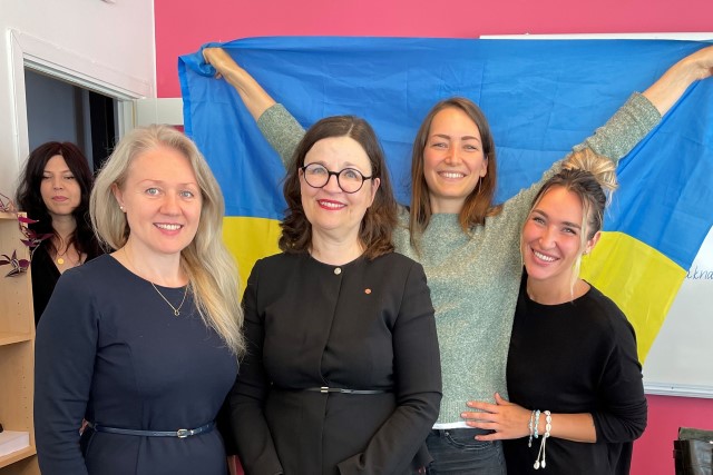 Utbildnignsminister Anna Ekström tillsammans med tre unga kvinnor från Ukraina. En av kvinnorna håller upp en Ukrainsk flagga bakom gruppen.