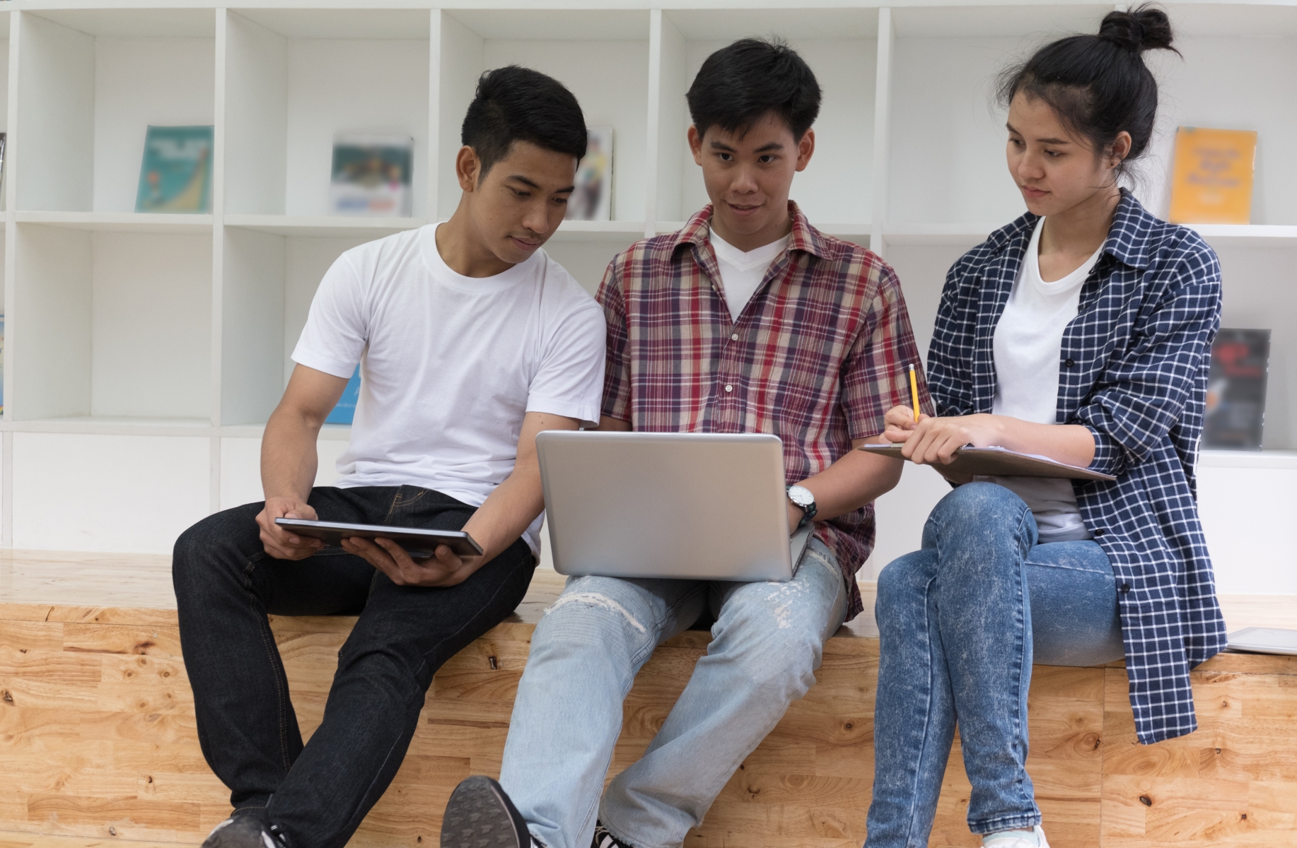 Tre studenter som sitter och tittar på en laptop.