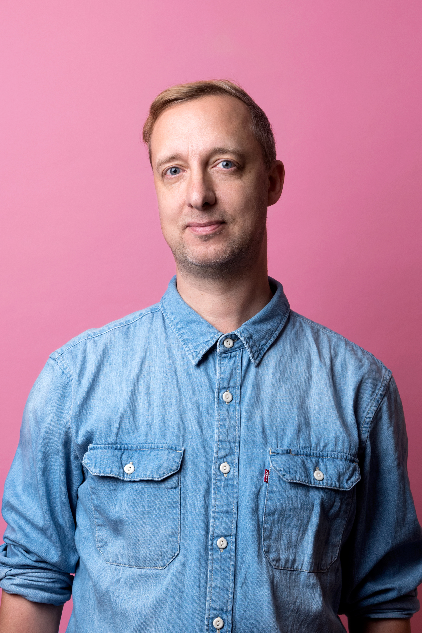 Peter tittar rakt in i kameran. Han är iklädd en blå jeansskjorta med upprullade armar.