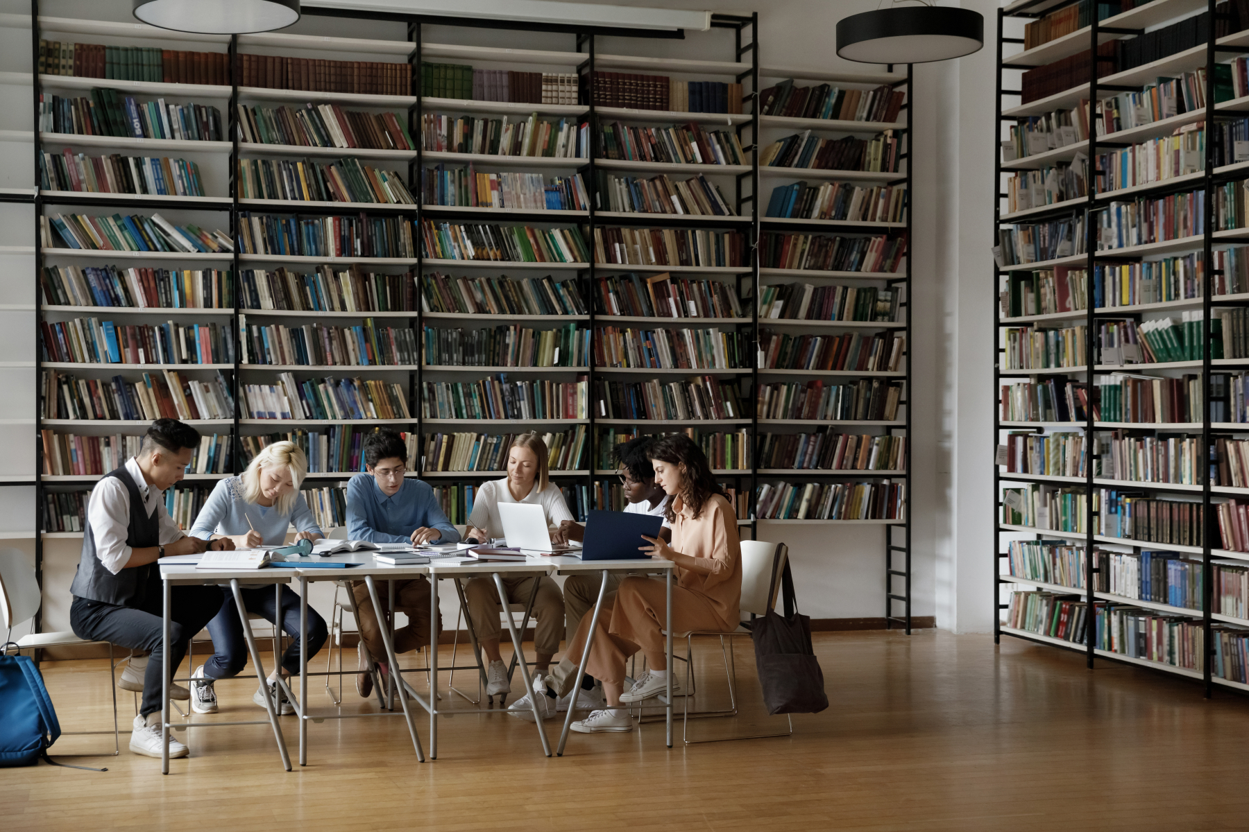 En grupp som sitter runt ett bord i ett bibliotek och studerar
