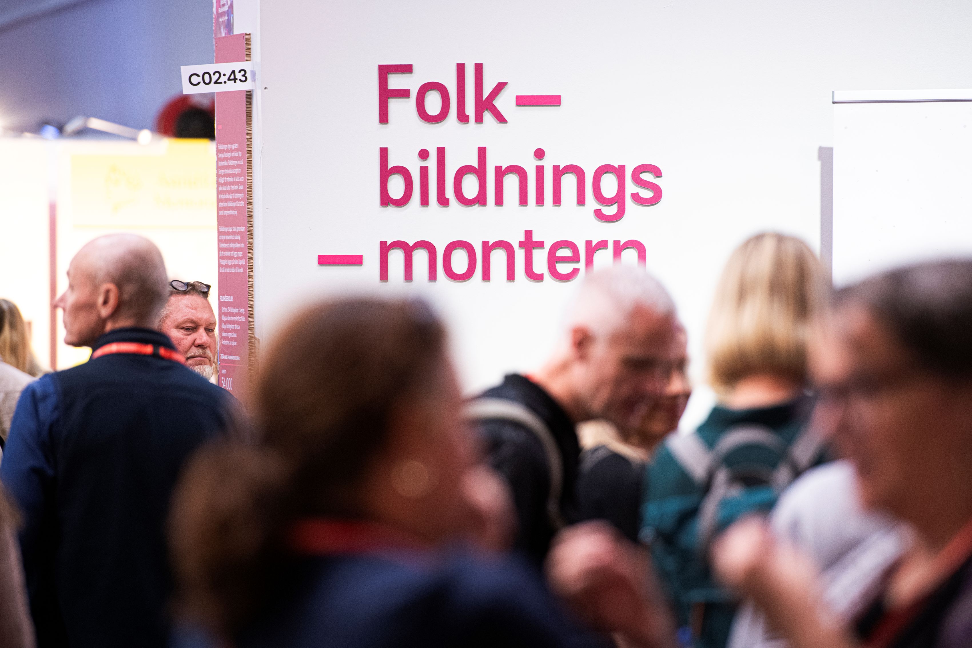 Ett myller av folk i förgrunden, i bakgrunden en vägg med texten "Folkbildningsmontern".