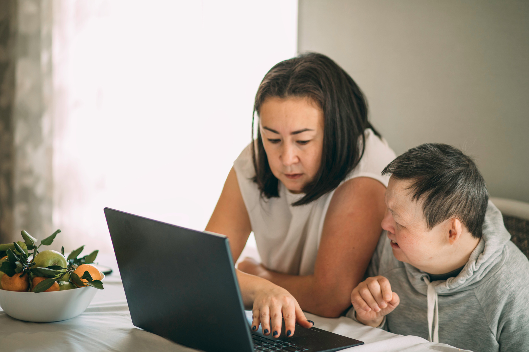 Två personer sitter framför en dator och arbetar tillsammans, en av personerna har downs syndrom.